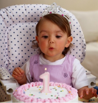Малыш задувает свечу на свой первый день рождения